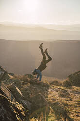 Male sportsperson exercising while doing handstand on mountain - RSGF00661