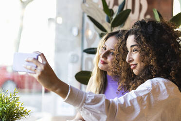 Multiethnische Freundinnen machen ein Selfie mit dem Handy im Restaurant - PNAF01499
