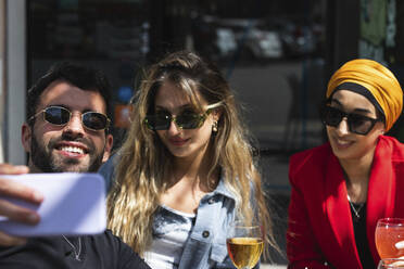 Young man taking selfie with female friends at bar - PNAF01513