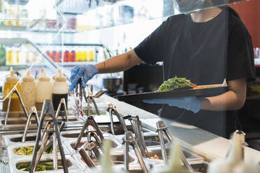 Kellnerin serviert Essen auf einem Tablett im Restaurant während COVID-19 - PNAF01516