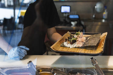 Kellnerin hält Essenstablett am Tresen eines Restaurants - PNAF01518