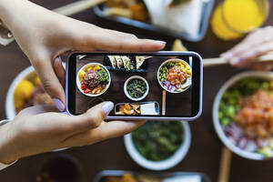 Junge Frau fotografiert Essen am Tisch im Restaurant - PNAF01526