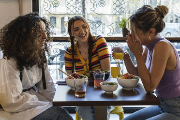 Fröhliche Freundinnen unterhalten sich in einem Restaurant - PNAF01528