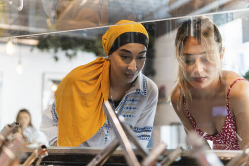 Freundinnen schauen durch die Vitrine im Restaurant - PNAF01548