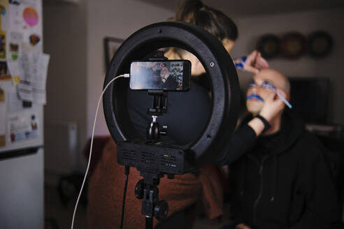 Maskenbildnerin mit Modell beim Vlogging im Studio - ASGF00256