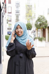 Junge Frau gestikuliert beim Telefonieren mit dem Handy - IFRF00520