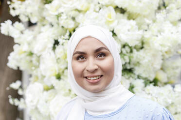 Schöne Frau trägt Hijab vor weißen Blumen - IFRF00559