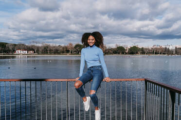 Smiling woman sitting on railing - EBBF03420