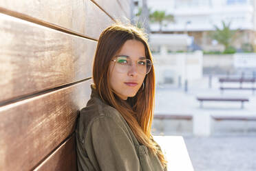 Schöne Frau mit Brille lehnt an einer Holzwand - DLTSF01839