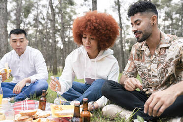 Männliche und weibliche Freunde essen Essen während einer Party im Wald - JCCMF02116