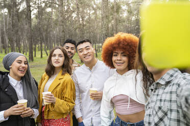 Friends taking selfie through smart phone while enjoying at forest - JCCMF02144