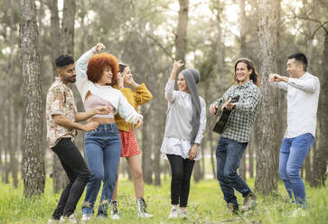 Male and female friends dancing and enjoying at forest - JCCMF02181