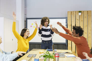 Happy business professionals cheering in board room at office - JSMF02142