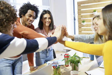 Business colleagues cheering together at board room in office - JSMF02143