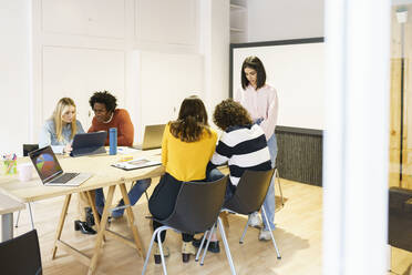 Multi-ethnic business colleagues discussing at conference table in office - JSMF02198