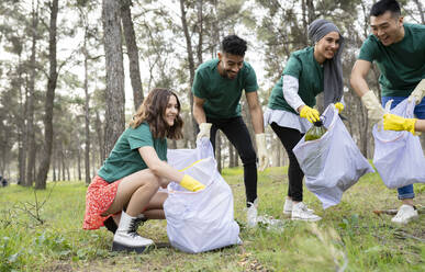 Mitarbeiter von Wohlfahrtsverbänden und Hilfsorganisationen sammeln im Wald Müll in Plastiksäcken - JCCMF02191