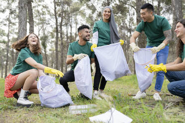 Young environmentalist friends collecting garbage in plastic bag at forest - JCCMF02193