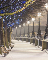UK, England, London, Reihen von Straßenlaternen beleuchten die leere South Bank Promenade im Winter - AHF00380