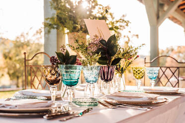 Close-up of served festive table with crystal glasses cutlery napkin on plate near bunch of fresh flowers for wedding and menu card - ADSF23740