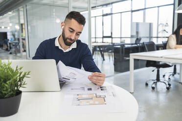 Männlicher Fachmann, der in einem Coworking-Büro ein Dokument liest - SNF01308