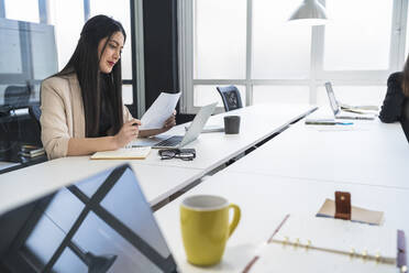 Female professional reading document in coworking office - SNF01315