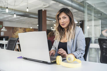 Businesswoman working on laptop at coworking office - SNF01319