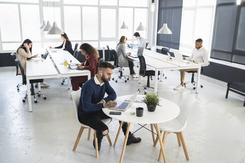 Male and female professionals working at coworking office - SNF01337