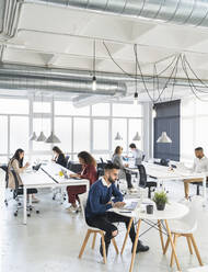 Männliche und weibliche Fachkräfte arbeiten an einem Laptop in einem Coworking-Büro - SNF01338
