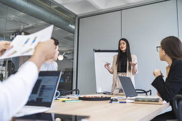 Unternehmerin gestikuliert bei der Erläuterung einer Strategie während einer Besprechung im Büro - SNF01363