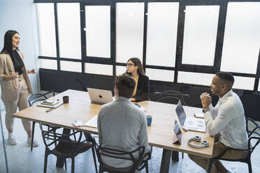 Geschäftsfrau bespricht Strategie mit männlichen und weiblichen Kollegen in einem Coworking-Büro - SNF01370