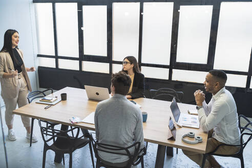 Geschäftsfrau bespricht Strategie mit männlichen und weiblichen Kollegen in einem Coworking-Büro - SNF01370