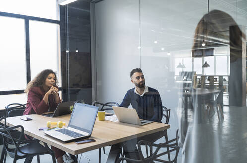 Male and female professionals looking at businesswoman in office - SNF01374