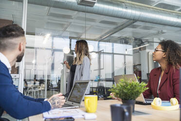 Female professional explaining strategy to colleagues in coworking office - SNF01379