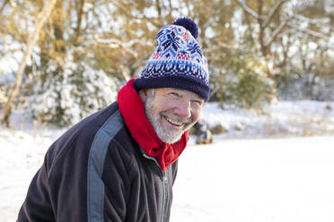 Smiling senior man in knit hat during winter - FVDF00117