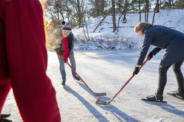 Älterer Mann spielt im Winter mit Freunden Eishockey im Schnee - FVDF00120