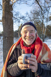 Lächelnder Mann mit Kaffeetasse im Winter - FVDF00129