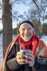 Smiling man with coffee cup during winter - FVDF00129