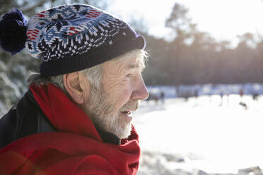 Älterer Mann mit rotem Schal und Strickmütze an einem sonnigen Tag im Winter - FVDF00134