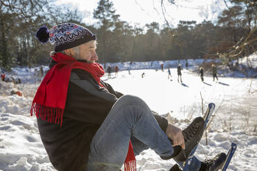 Senior man wearing ice skate during winter - FVDF00136