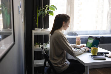 Frau benutzt Laptop bei der Arbeit zu Hause - VPIF03912