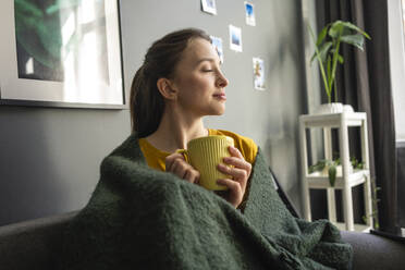 Woman wrapped in blanket holding coffee cup at home - VPIF03936