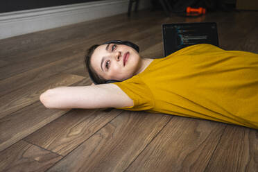 Woman with headphones day dreaming while resting on floor at home - VPIF03946