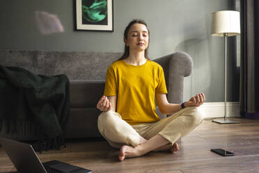 Young woman meditating while sitting at home - VPIF03947