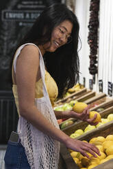 Young woman buying lemons from grocery store - PNAF01565