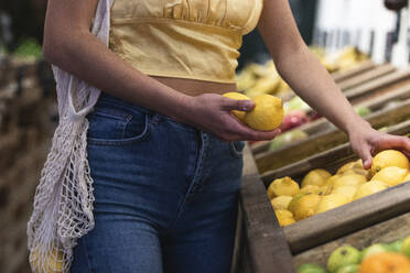 Woman holding lemons at store - PNAF01566