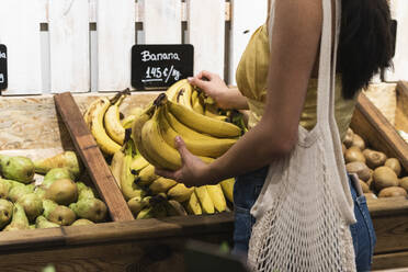 Woman choosing bananas at grocery store - PNAF01568