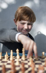 Intelligenter Junge spielt Schach vor einer Wand - GISF00797