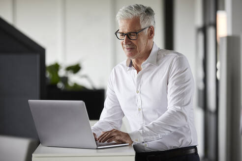 Männlicher Unternehmer mit Laptop bei der Arbeit im Büro - RBF08101