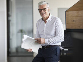 Entrepreneur holding paper while smiling in office - RBF08126