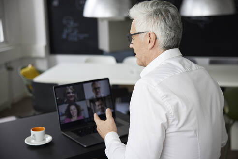 Geschäftsmann im Gespräch mit Kollegen per Videoanruf über Laptop im Büro - RBF08131